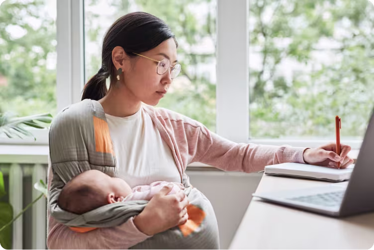 Maternity Pay 1 Maternity pay banner image of a woman holding ababy writing by a desk
